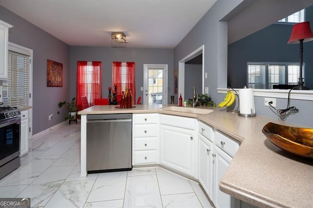 kitchen with kitchen peninsula, white cabinets, appliances with stainless steel finishes, and sink