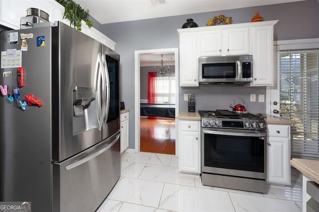 kitchen with stainless steel appliances, a chandelier, and white cabinetry