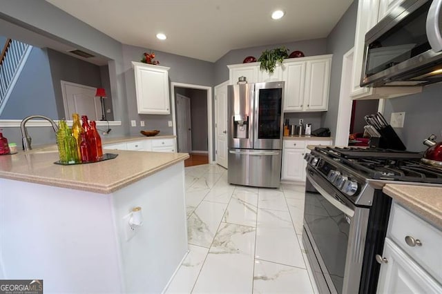 kitchen with appliances with stainless steel finishes, white cabinetry, a kitchen island, and sink