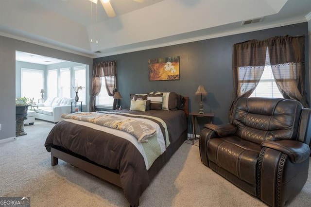 bedroom featuring light colored carpet, ceiling fan, a tray ceiling, and crown molding