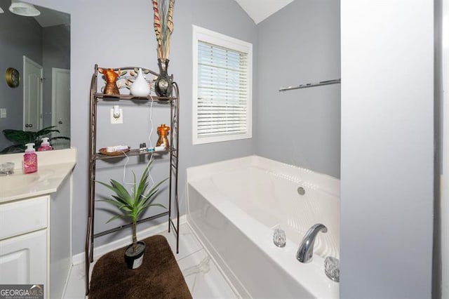 bathroom featuring lofted ceiling, vanity, and a bathing tub