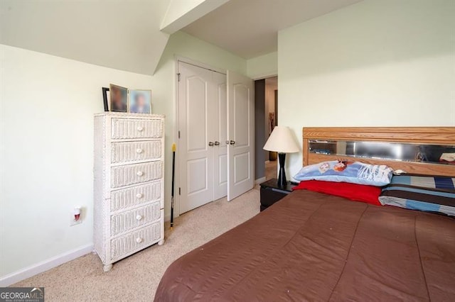 carpeted bedroom with a closet and vaulted ceiling