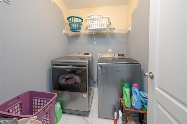 clothes washing area featuring light tile patterned flooring and washing machine and clothes dryer