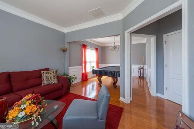 living room with pool table, an inviting chandelier, crown molding, and hardwood / wood-style flooring