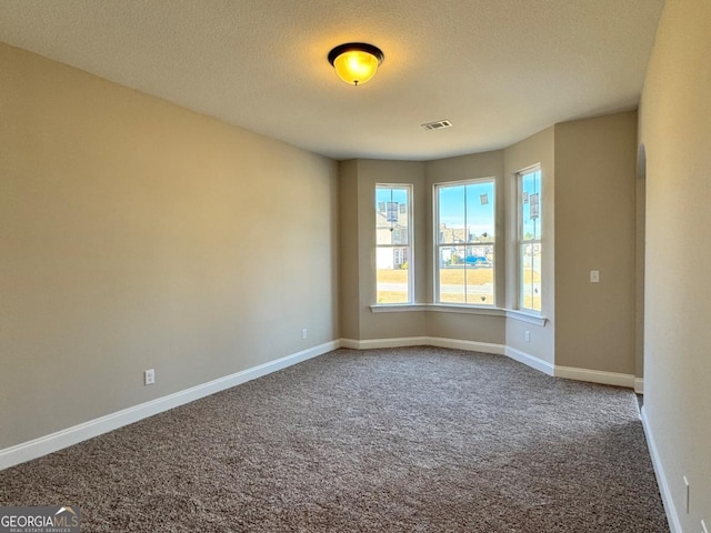 empty room with a textured ceiling and carpet