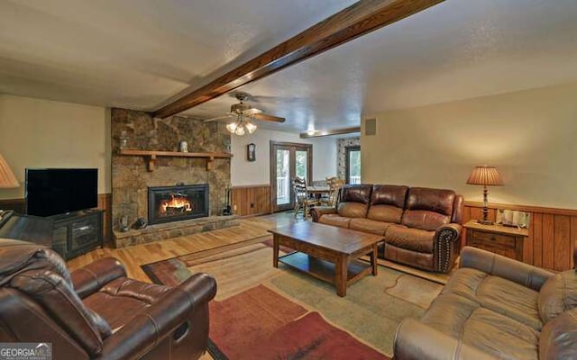 living room with a fireplace, french doors, ceiling fan, light hardwood / wood-style floors, and beam ceiling