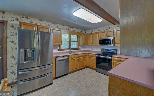 kitchen with appliances with stainless steel finishes, beamed ceiling, and sink