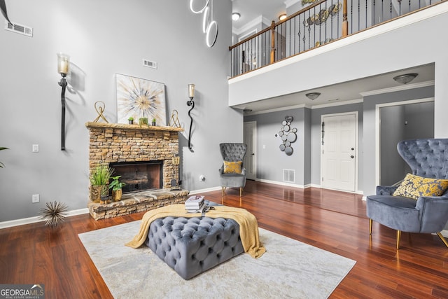 living room featuring a high ceiling, dark hardwood / wood-style floors, ornamental molding, and a fireplace