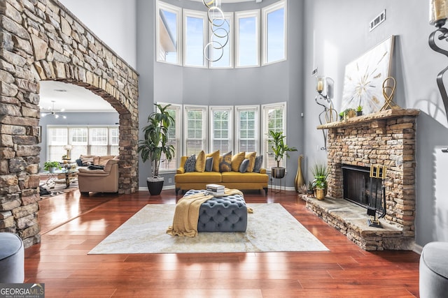 living room featuring hardwood / wood-style floors, a towering ceiling, and a stone fireplace