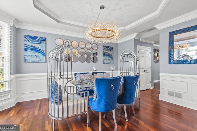 dining area with ornamental molding, dark hardwood / wood-style flooring, a raised ceiling, and a chandelier