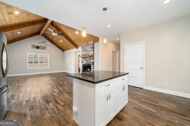 kitchen with pendant lighting, dark hardwood / wood-style floors, white cabinets, dark stone counters, and a fireplace