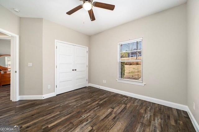 unfurnished bedroom with dark hardwood / wood-style flooring, a closet, and ceiling fan