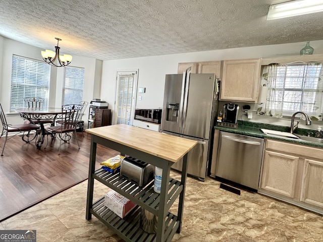 kitchen featuring sink, decorative light fixtures, light brown cabinets, a notable chandelier, and stainless steel appliances