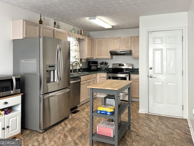 kitchen with sink, stainless steel appliances, a textured ceiling, and light brown cabinets