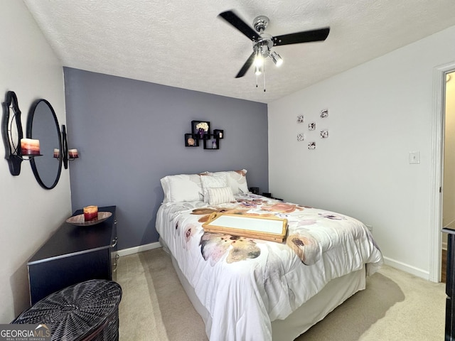 bedroom featuring a textured ceiling, light colored carpet, and ceiling fan