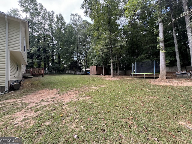 view of yard with a deck, a trampoline, and a storage shed