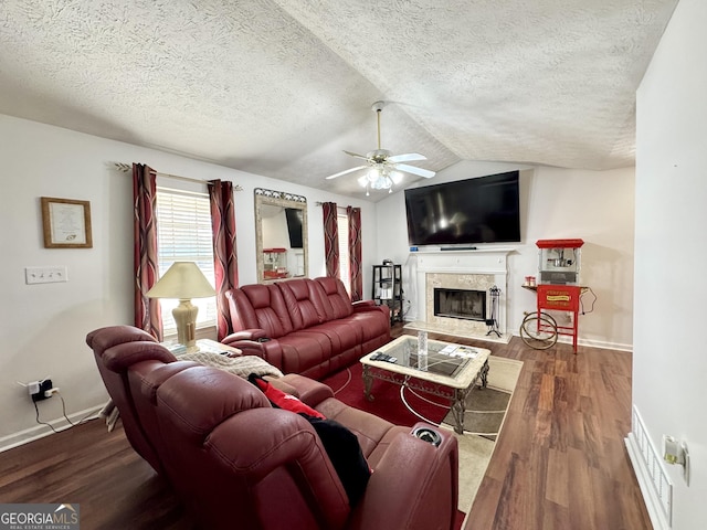 living room featuring lofted ceiling, hardwood / wood-style flooring, ceiling fan, a premium fireplace, and a textured ceiling