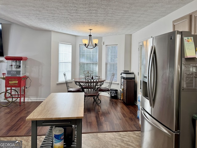 kitchen featuring hanging light fixtures, stainless steel refrigerator with ice dispenser, a textured ceiling, and a chandelier