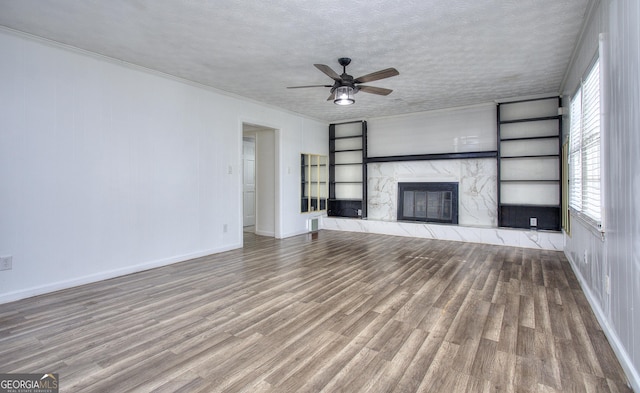 unfurnished living room with a textured ceiling, plenty of natural light, a high end fireplace, and built in shelves