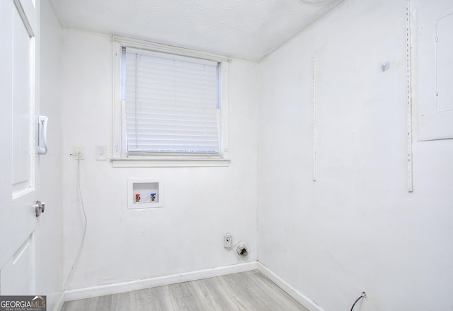 clothes washing area with a textured ceiling, light hardwood / wood-style flooring, and washer hookup