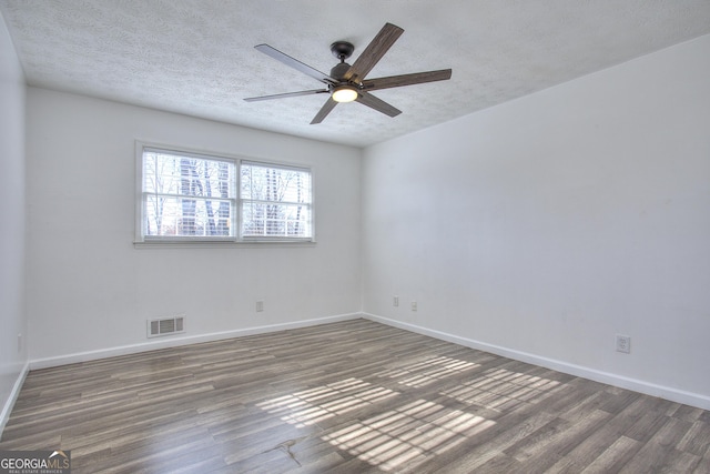 spare room with a textured ceiling, dark hardwood / wood-style flooring, and ceiling fan