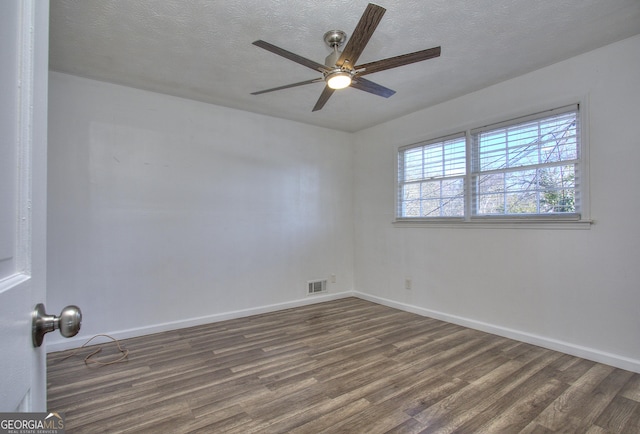 spare room with a textured ceiling, ceiling fan, and dark hardwood / wood-style floors