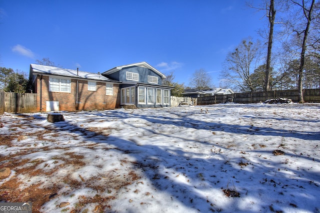 snow covered house featuring a sunroom