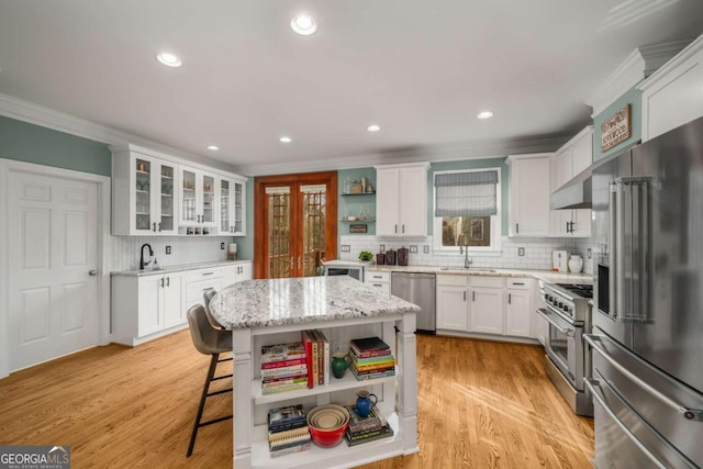 kitchen with sink, white cabinetry, light stone counters, a kitchen island, and premium appliances