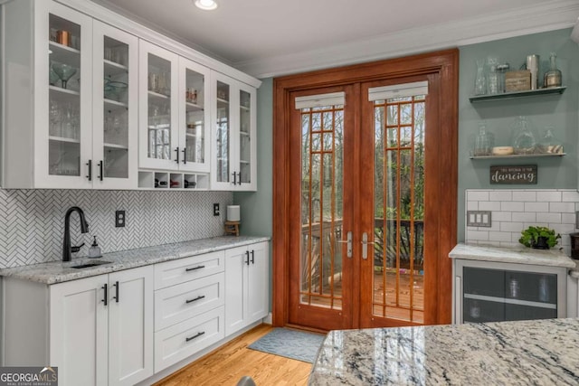 interior space featuring sink, light stone countertops, french doors, and white cabinetry