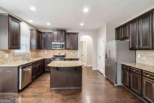 kitchen featuring appliances with stainless steel finishes, dark wood-type flooring, dark brown cabinets, and a kitchen island