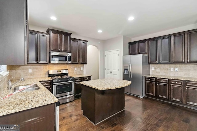 kitchen featuring a center island, stainless steel appliances, backsplash, dark hardwood / wood-style flooring, and sink