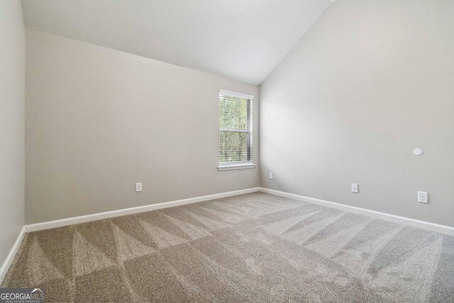 spare room featuring lofted ceiling and carpet flooring