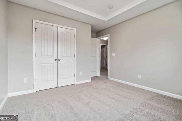 unfurnished bedroom with light colored carpet and a closet