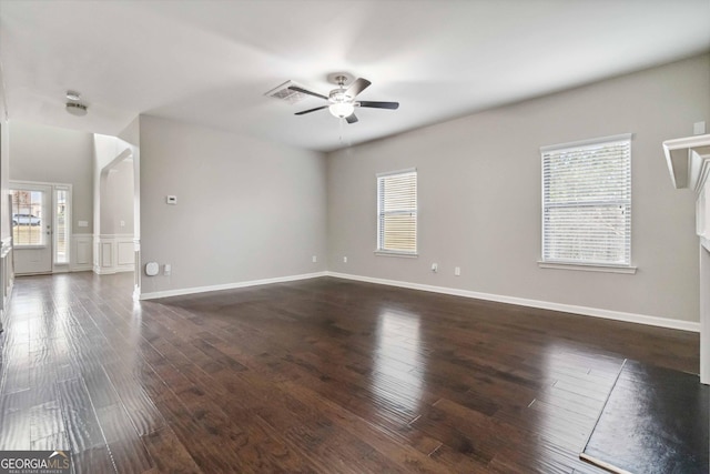 empty room with ceiling fan, a wealth of natural light, and dark hardwood / wood-style floors