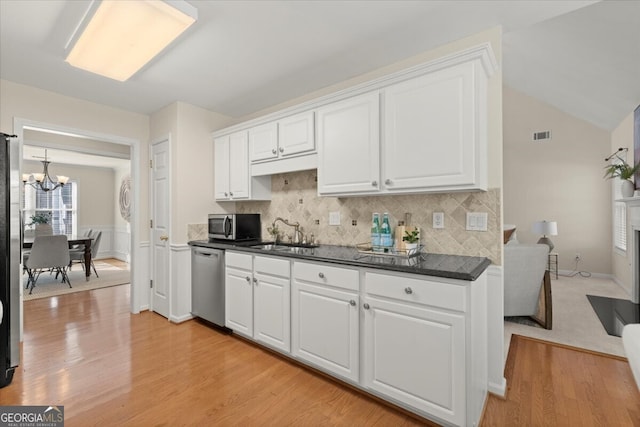 kitchen with sink, appliances with stainless steel finishes, a chandelier, and white cabinetry