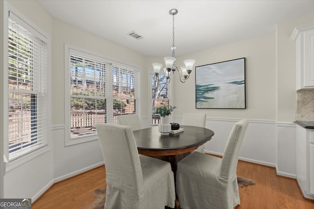 dining space with a healthy amount of sunlight, light wood-type flooring, and a chandelier