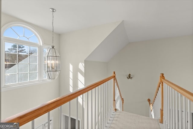 corridor with an inviting chandelier and lofted ceiling