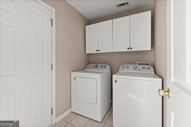 laundry room with washing machine and dryer, cabinets, and light tile patterned floors