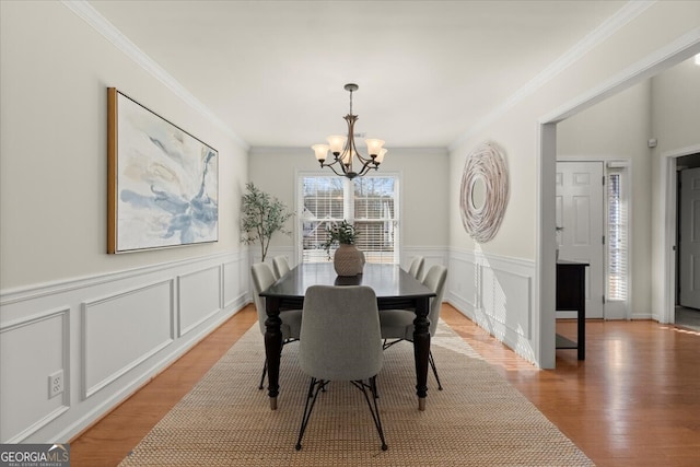 dining room with crown molding, light hardwood / wood-style flooring, and a chandelier