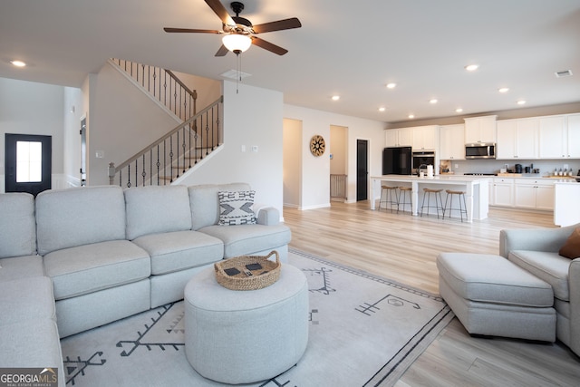 living room featuring sink, light hardwood / wood-style floors, and ceiling fan