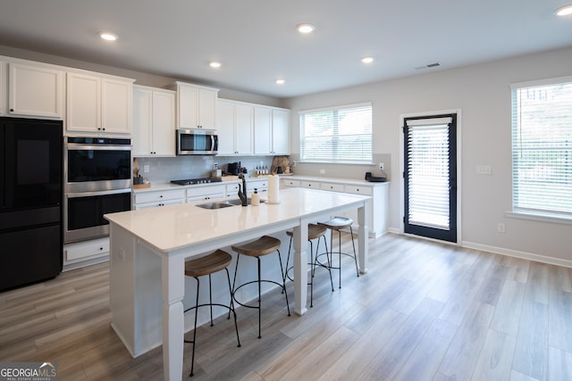 kitchen featuring white cabinetry, sink, a breakfast bar area, a kitchen island with sink, and stainless steel appliances