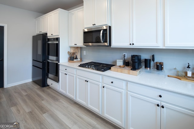 kitchen with backsplash, stainless steel appliances, light hardwood / wood-style floors, and white cabinets