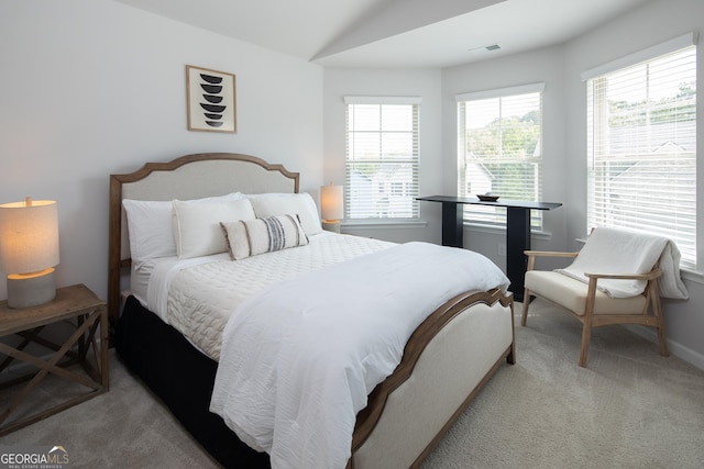 bedroom with light carpet, multiple windows, and vaulted ceiling