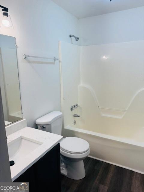 full bathroom featuring bathing tub / shower combination, toilet, vanity, and hardwood / wood-style flooring