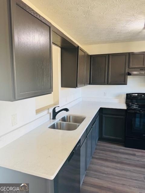 kitchen featuring black appliances, dark hardwood / wood-style floors, dark brown cabinetry, a textured ceiling, and sink