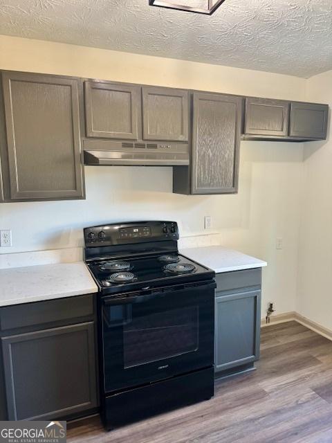 kitchen featuring black electric range, a textured ceiling, hardwood / wood-style floors, and gray cabinetry