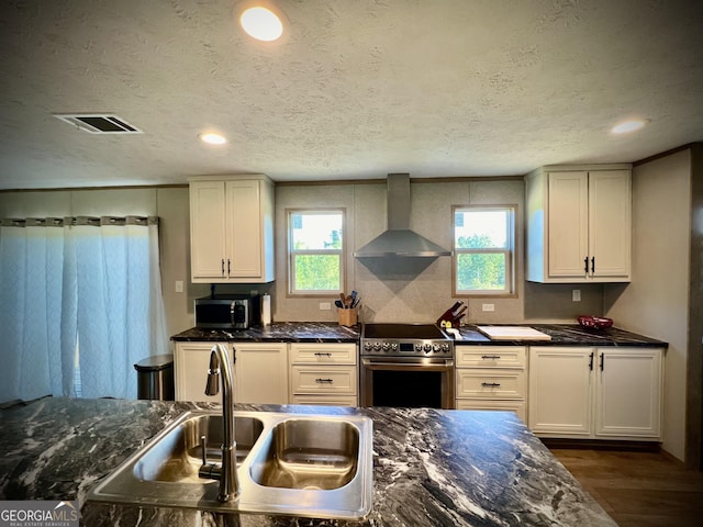 kitchen with stainless steel appliances, sink, white cabinetry, dark hardwood / wood-style floors, and wall chimney range hood