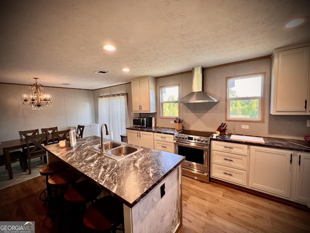 kitchen featuring a center island with sink, stainless steel appliances, a breakfast bar, wall chimney exhaust hood, and sink