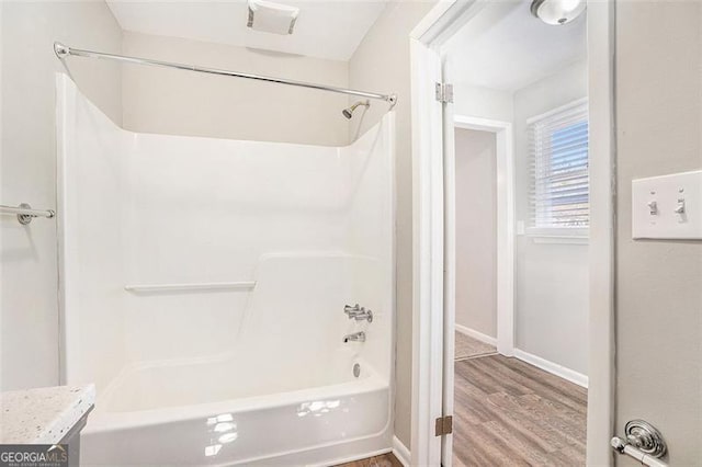 bathroom featuring hardwood / wood-style flooring and washtub / shower combination