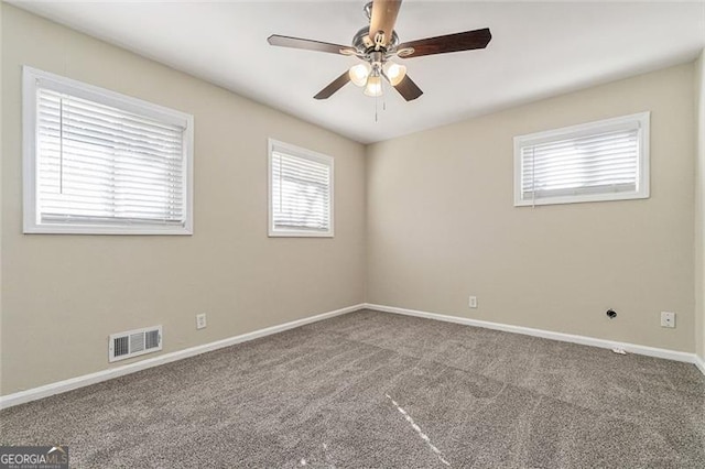 carpeted spare room featuring ceiling fan and a healthy amount of sunlight